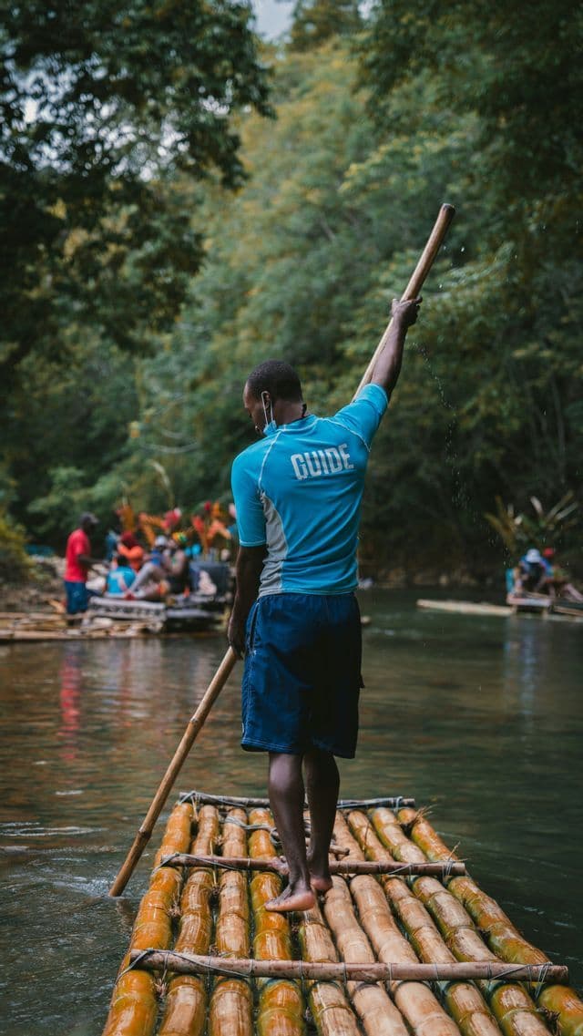 From behind, a guide steers a bamboo raft with a pole on a river, with a WeRoad group trip in the background.