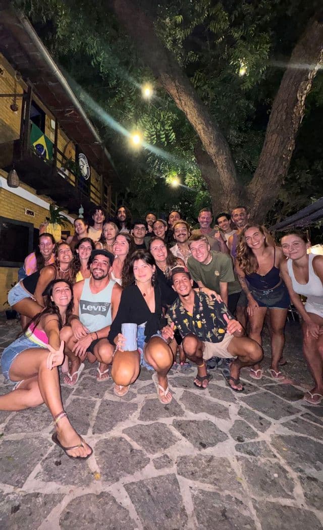 Un gruppo WeRoad posa per una foto di notte su un patio di ciottoli sotto un grande albero con luci a catena.