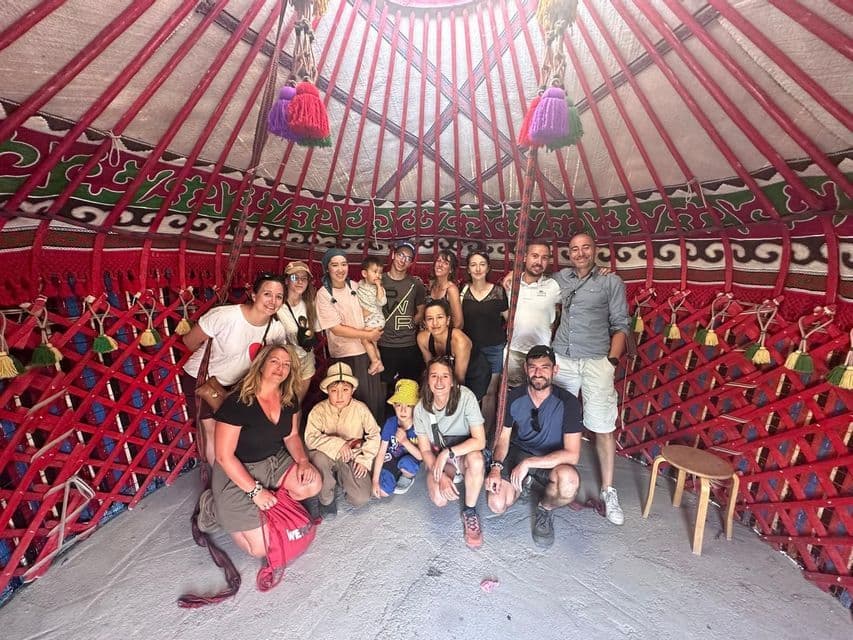 Un voyage de groupe WeRoad posant pour une photo à l'intérieur d'une yourte traditionnelle avec des murs décoratifs en treillis rouge.