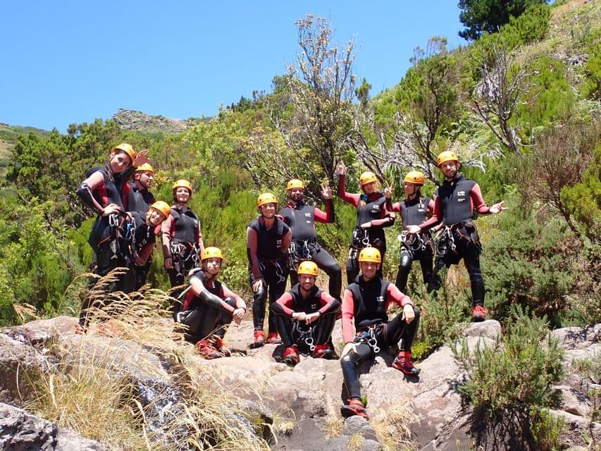 Un groupe WeRoad en combinaisons de plongée et casques jaunes pose pour une photo sur une colline rocheuse sous un ciel bleu clair.