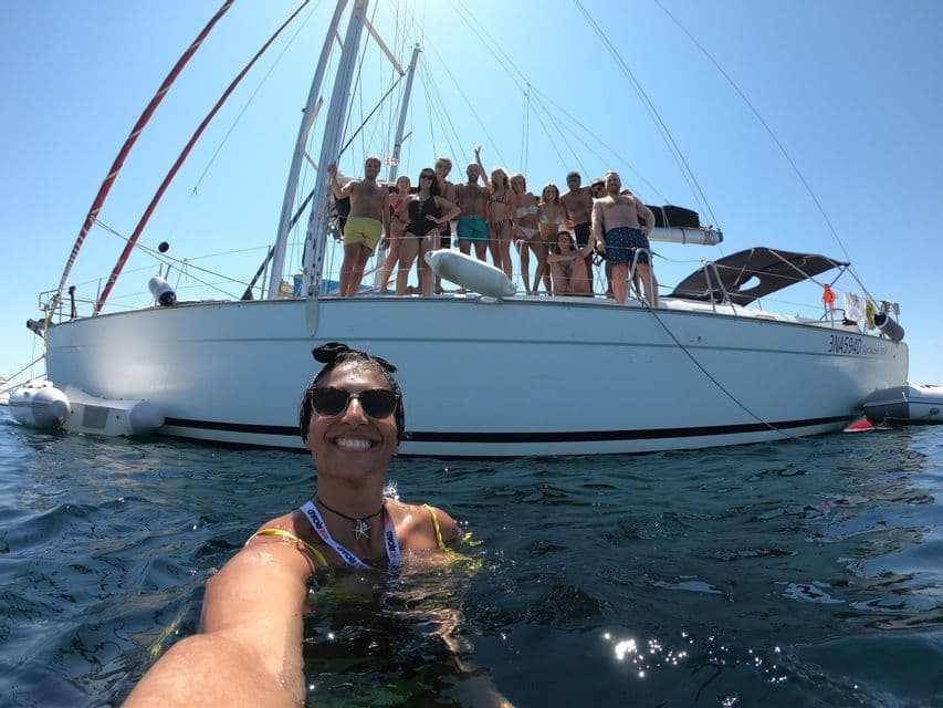 Una donna sorridente si scatta un selfie dall'acqua mentre un viaggio di gruppo WeRoad posa sul ponte di una barca a vela.