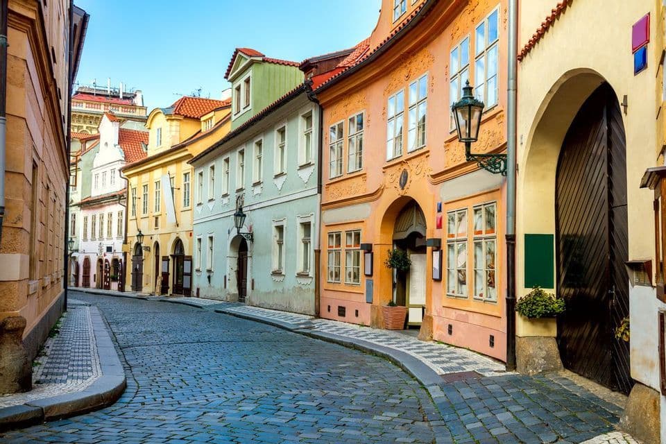 Une rue pavée sinueuse bordée de bâtiments historiques colorés sous un ciel bleu dégagé.