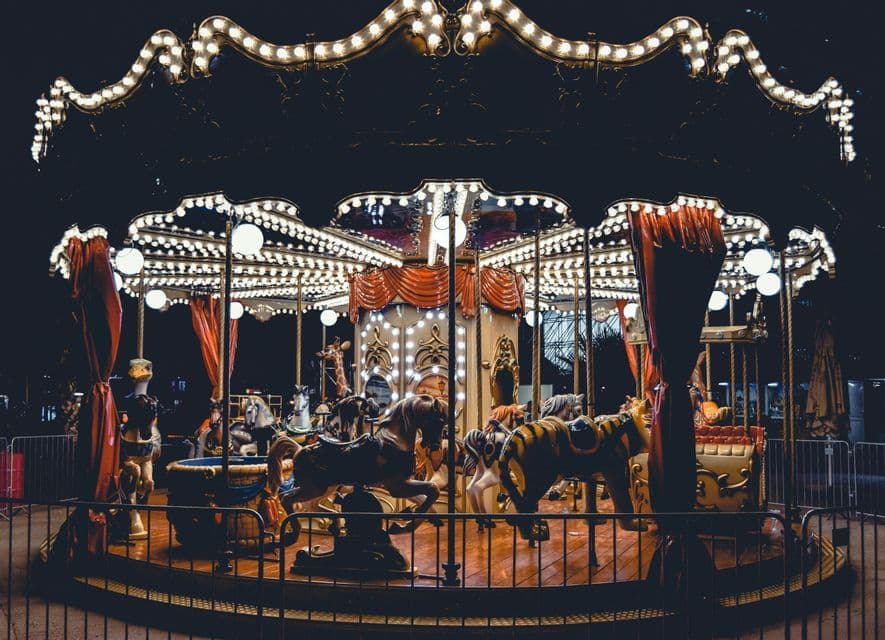 Un carosello vintage vuoto con cavalli e altri animali, vivacemente illuminato di notte da luci calde.