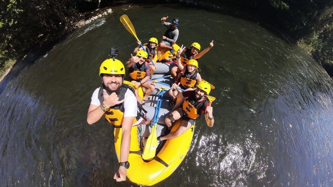 Un selfie dall'alto di un gruppo WeRoad sorridente e in posa in un gommone giallo mentre scende un fiume.