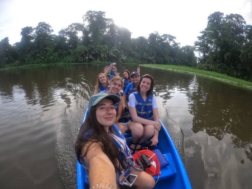 Une femme prend un selfie de son voyage de groupe WeRoad lors d'une excursion en bateau le long d'une rivière bordée d'une jungle luxuriante.