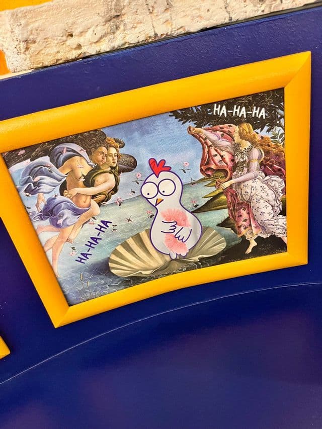 Una obra de arte enmarcada, parodia de 'El nacimiento de Venus', con un pollo de dibujos animados reemplazando la figura central sobre una concha marina.