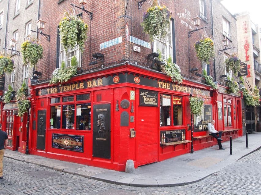 L'esterno del pub The Temple Bar, con la sua vivace facciata rossa su un angolo di strada acciottolata e cesti di fiori appesi.