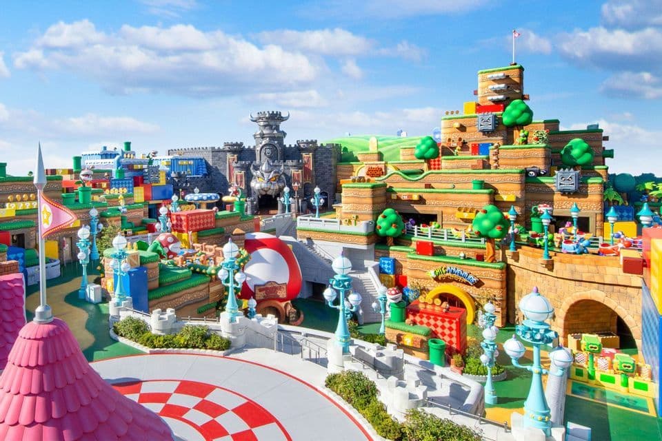 Una veduta panoramica del parco a tema Super Nintendo World, con il Castello di Bowser e paesaggi colorati a blocchi sotto un cielo azzurro.