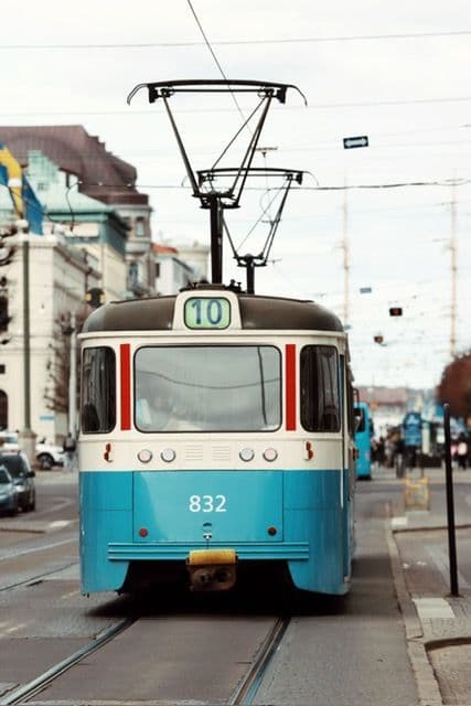 Front view of a blue, cream, and red vintage tram on tracks running down a city street.