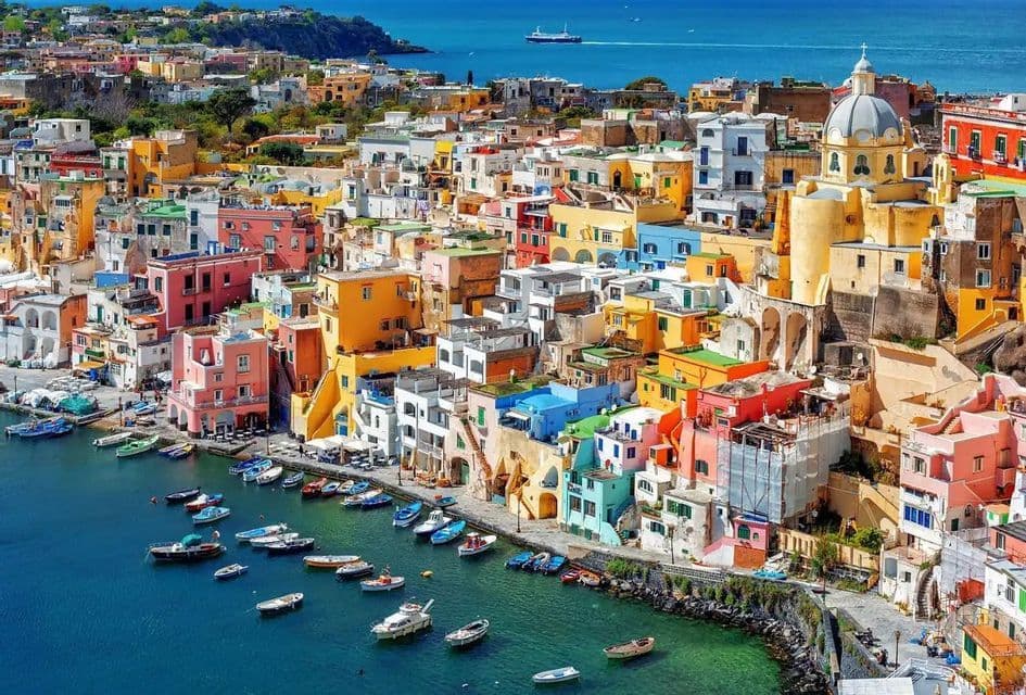 A high-angle view of colorful houses built on a steep cliff overlooking a harbor filled with small boats.