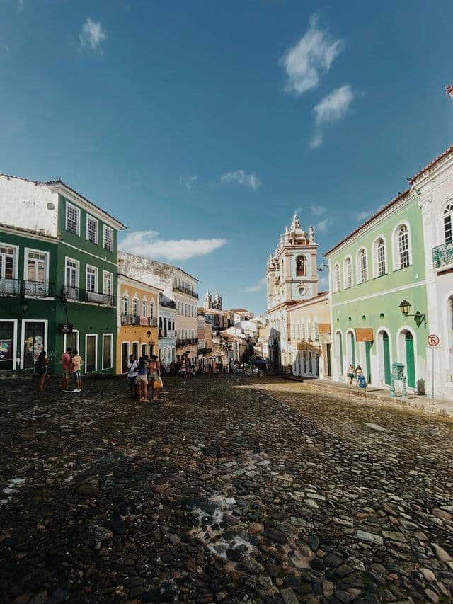 Un viaggio di gruppo WeRoad su un'ampia strada di ciottoli fiancheggiata da colorati edifici coloniali sotto un cielo azzurro brillante.