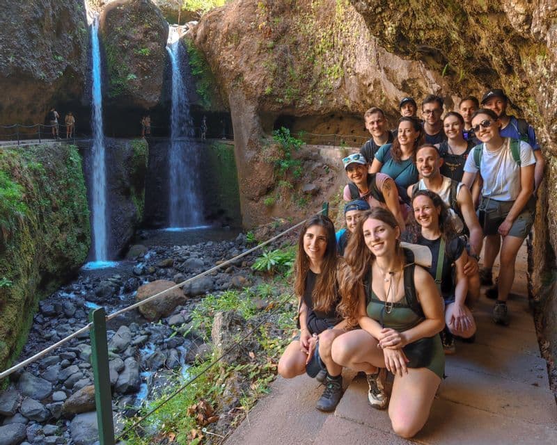 Un gruppo WeRoad sorride per una foto su un sentiero roccioso accanto a due cascate.