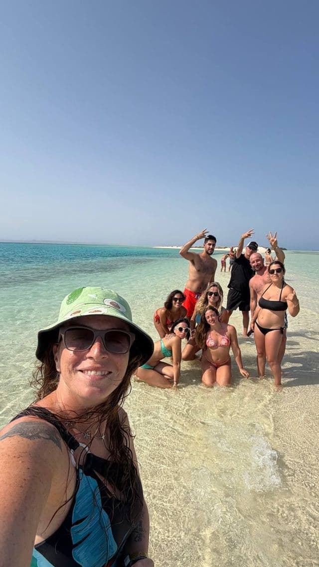 Un gruppo WeRoad in viaggio si scatta un selfie nelle acque basse e turchesi di un banco di sabbia in una giornata di sole.