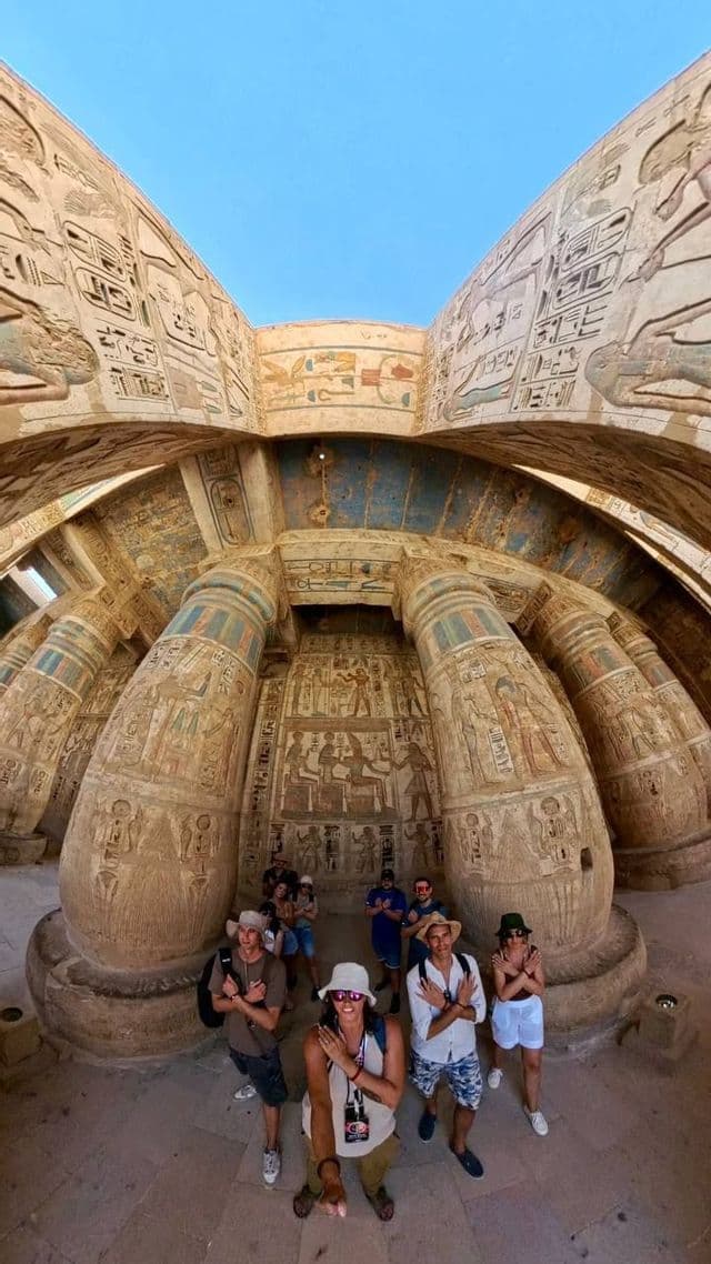Un gruppo WeRoad in posa all'interno di un antico tempio egizio con grandi colonne coperte di geroglifici.