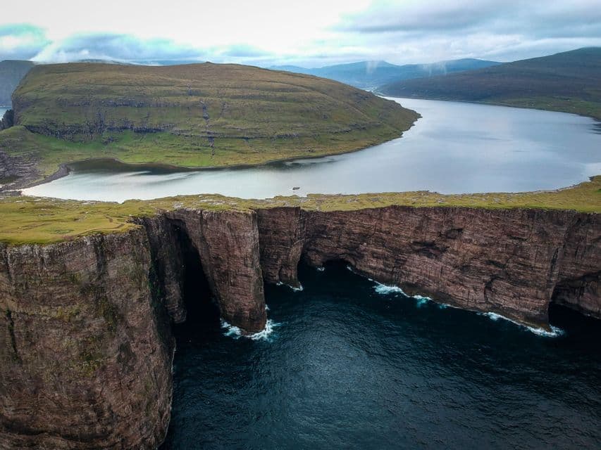 Veduta aerea di un grande lago su un altopiano erboso, a picco sull'oceano e accanto a scogliere rocciose.