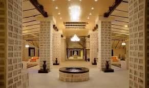 The interior of a spacious hall with large square pillars and walls constructed from blocks of salt, illuminated by ceiling lights.