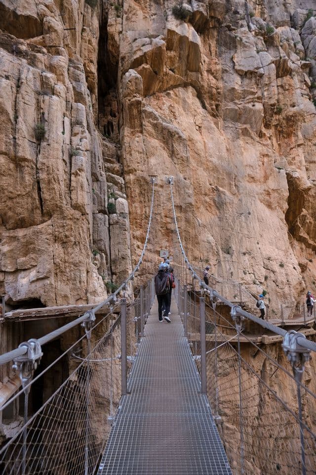 Un'escursione di gruppo WeRoad su uno stretto ponte sospeso aggrappato a una ripida parete del canyon.