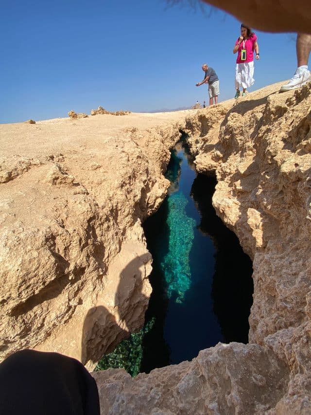 Un viaje en grupo de WeRoad de pie al borde de un estrecho abismo rocoso, contemplando las claras aguas turquesas que lo llenan.