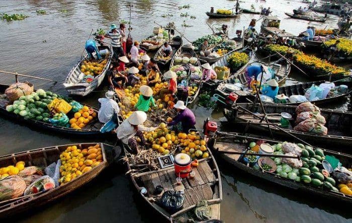 Une vue aérienne d'un marché flottant animé, avec de nombreux bateaux remplis de fruits frais, de légumes et de fleurs.