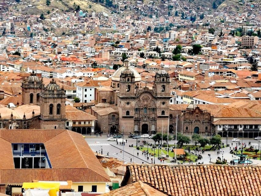 Ein erhöhter Blick auf eine historische Stadt mit zentraler Kathedrale und Platz, umgeben von Gebäuden mit roten Ziegeldächern auf einem Hügel.