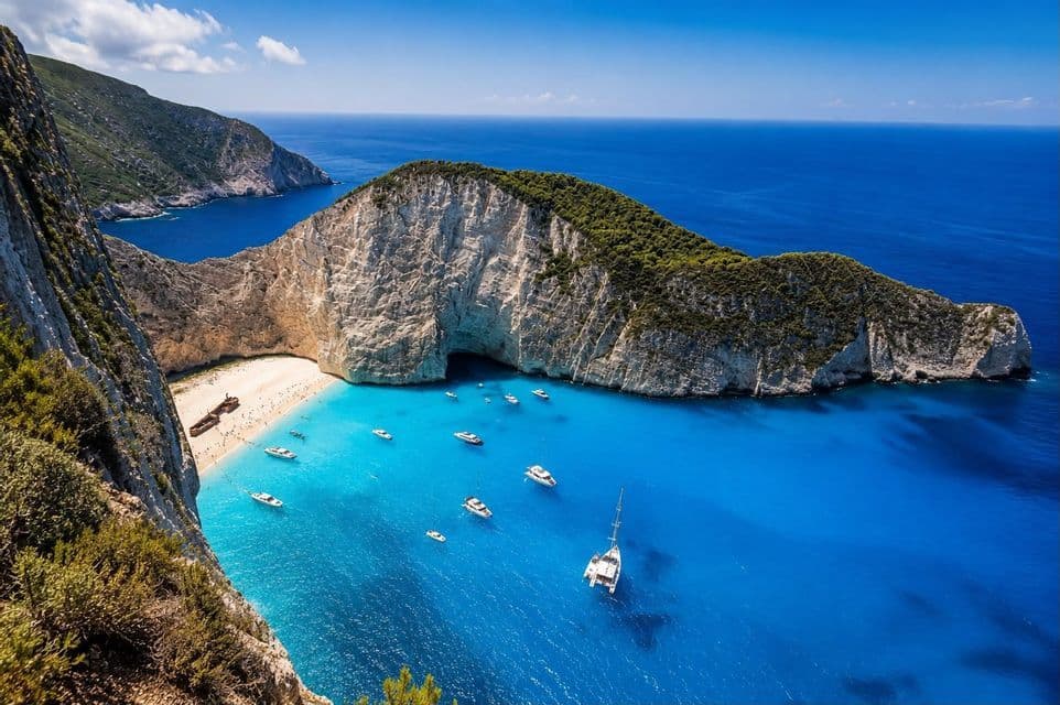Una vista dall'alto di un relitto su una baia sabbiosa, con barche ancorate nel mare turchese accanto a ripide scogliere bianche.