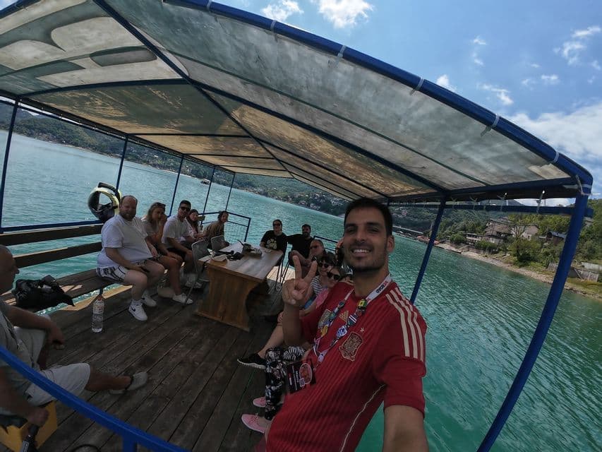 Ein Mann macht ein lächelndes Selfie mit einer WeRoad Gruppenreise auf einem überdachten Bootsausflug an einem sonnigen Tag.
