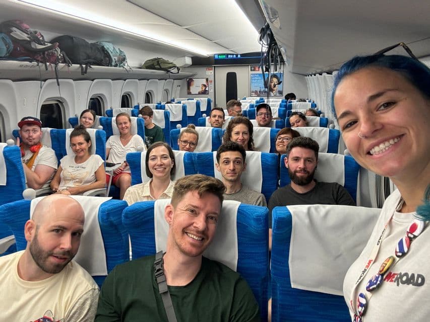 Eine große WeRoad-Gruppe lächelt für ein Selfie in einem modernen Zugabteil.