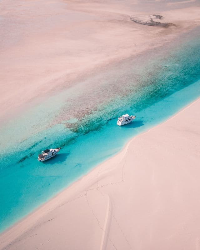 Boats anchored by a white sandbar in the Bahamas