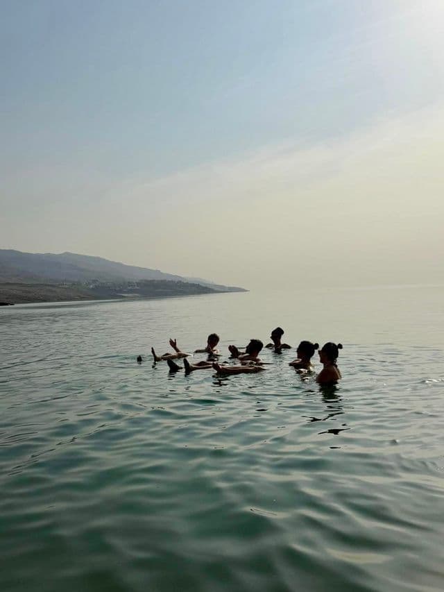 Eine WeRoad-Gruppe treibt gemeinsam auf ruhigem Wasser mit fernen Bergen am Horizont.