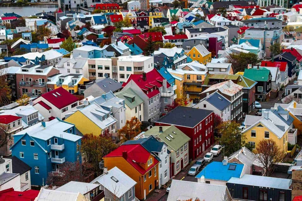 Una veduta aerea di una fitta città con case dipinte in colori vivaci come rosso, blu e giallo.