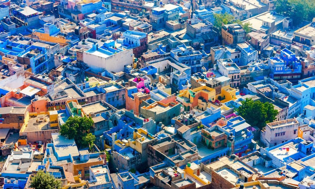 Eine Luftaufnahme einer dichten Stadtlandschaft mit Gebäuden in Blau-, Rosa- und Orangetönen.