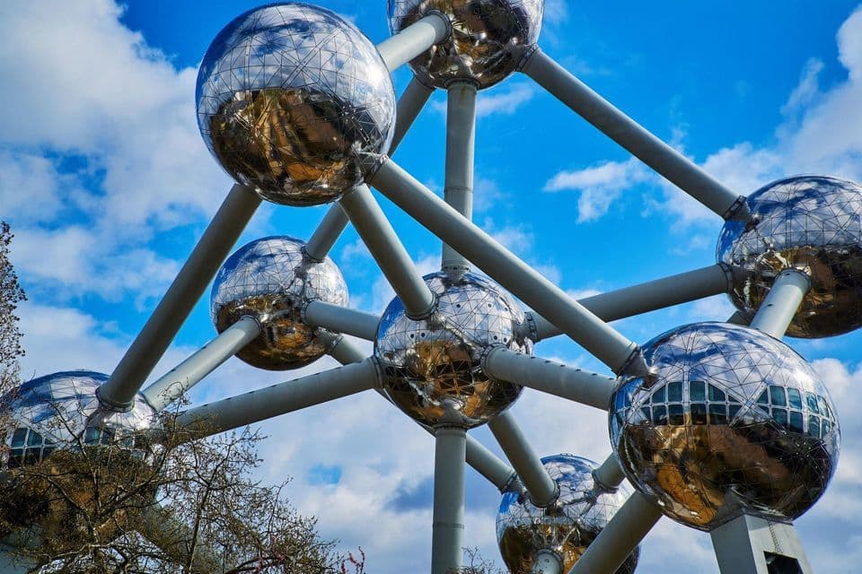 Una grande struttura metallica futuristica di sfere riflettenti interconnesse si erge contro un cielo blu con nuvole sparse.