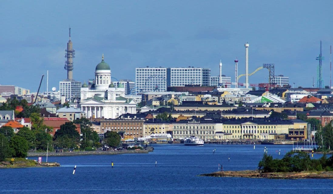Un panorama urbain avec une cathédrale blanche au dôme vert, visible depuis une baie bleue par temps clair.