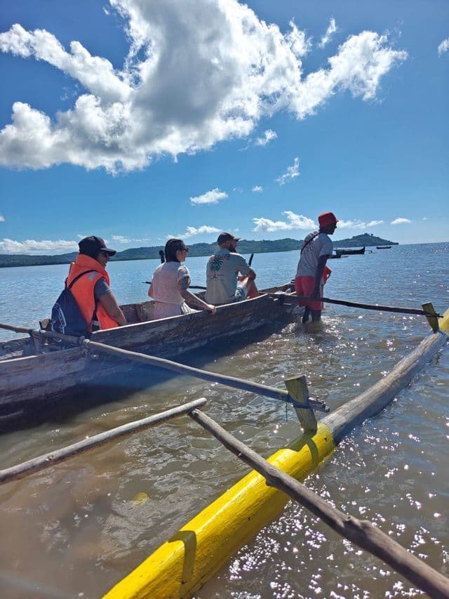 Un voyage de groupe WeRoad en pirogue à balancier en bois, poussé par un guide sur l'eau par une journée ensoleillée.