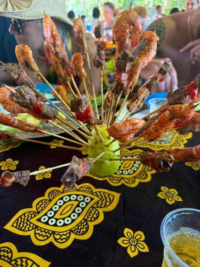 Brochettes de crevettes et de viande grillées, présentées avec des agrumes sur une nappe à motifs, dégustées par un groupe de voyage WeRoad.