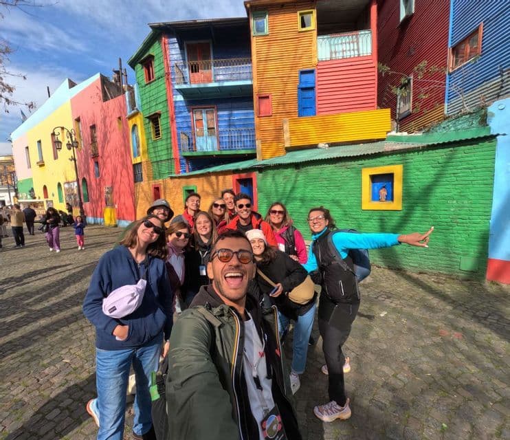 Eine WeRoad-Gruppe macht ein fröhliches Selfie auf einer Kopfsteinpflasterstraße vor bunten Gebäuden.