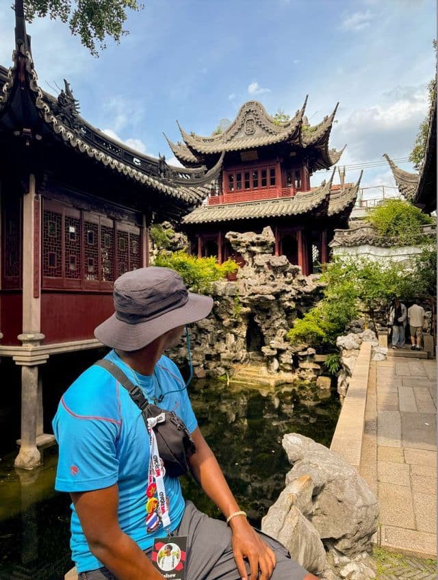 Ein Teilnehmer einer WeRoad-Gruppenreise sitzt an einem Teich und bewundert traditionelle Pagoden in einem chinesischen Garten.