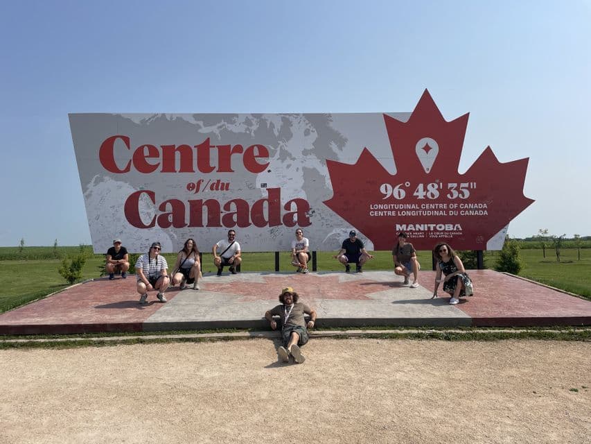 Un gruppo WeRoad in posa davanti alla grande insegna 'Centro del Canada' sotto un cielo sereno.