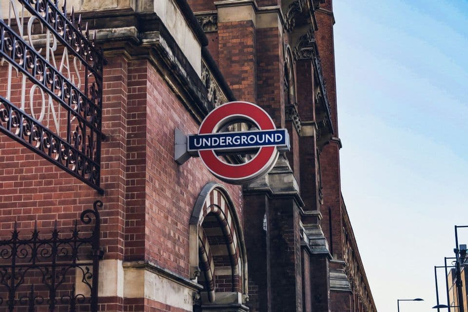 Un cartello tondo della metropolitana montato sul muro esterno in mattoni rossi di uno storico edificio in stile vittoriano.