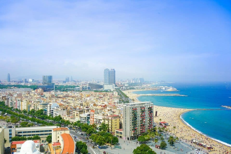 Vista elevada del horizonte de una ciudad costera que se encuentra con una playa de arena y aguas azules del océano en un día soleado
