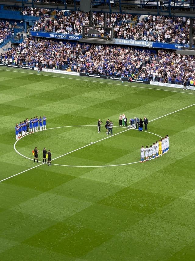 Due squadre di calcio e gli arbitri intorno al cerchio di centrocampo di un campo da gioco durante la cerimonia pre-partita