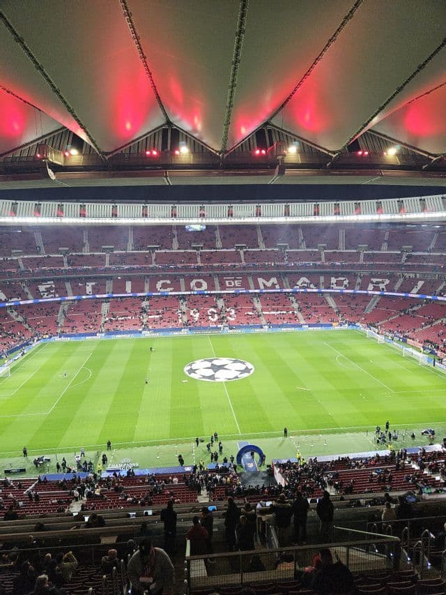 Vista dall'alto di un grande stadio di calcio con struttura del tetto illuminata che si affaccia su un campo da calcio verde