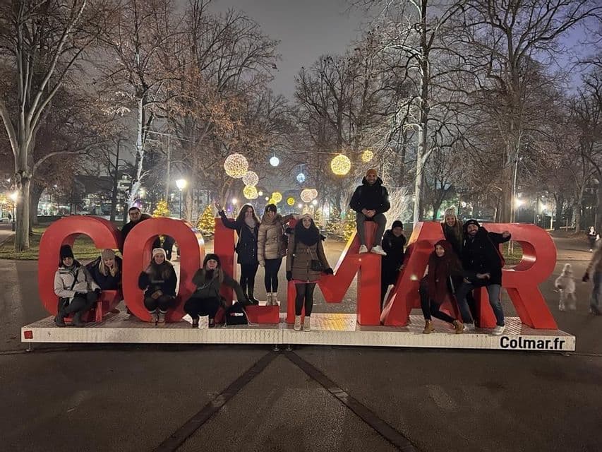 Un viaggio di gruppo WeRoad di persone in posa su grandi lettere rosse in un parco all'aperto illuminato di notte.