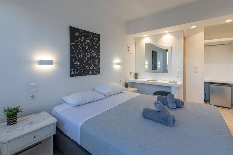 Una camera d'albergo con un letto matrimoniale, asciugamani arrotolati, moderna arte da parete in bianco e nero e una zona toeletta con specchio.