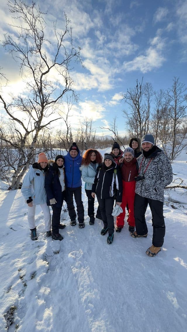 Un gruppo WeRoad in posa per una foto insieme in un paesaggio innevato con alberi spogli.