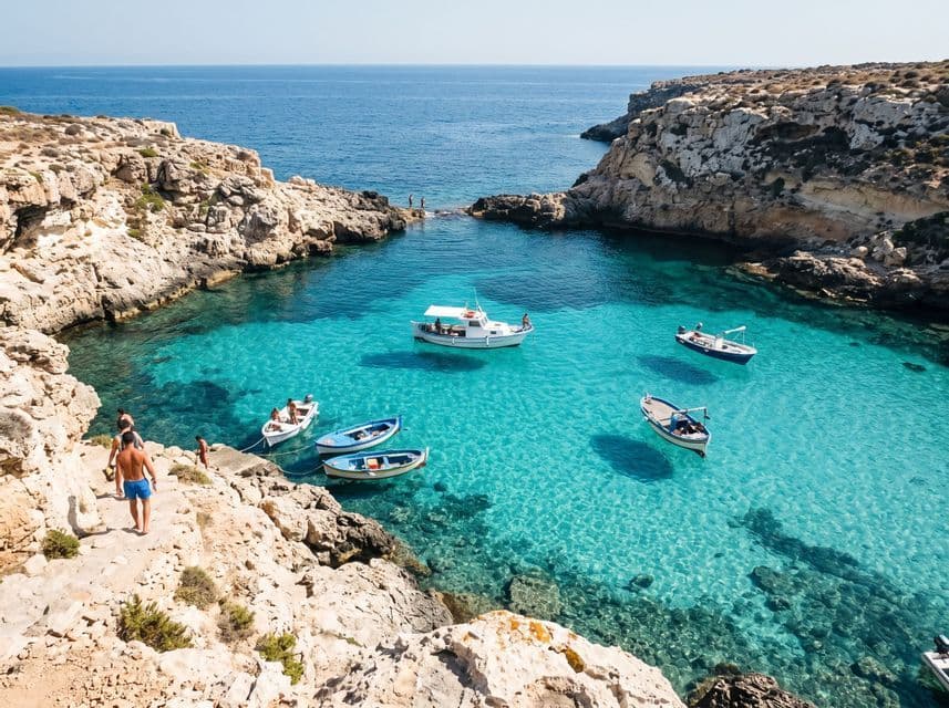 Piccole barche galleggiano su limpide acque turchesi in una baia rocciosa della costa con persone che camminano lungo le scogliere