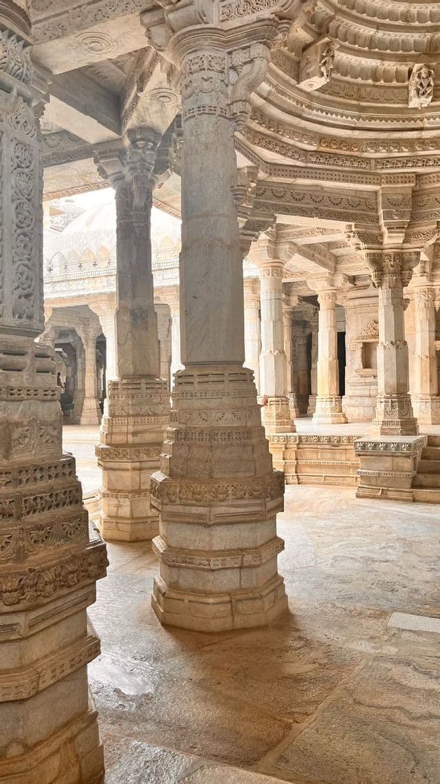 L'interno di un tempio storico, ricco di numerose colonne in pietra finemente intagliate che sorreggono un soffitto dettagliato e ornato.