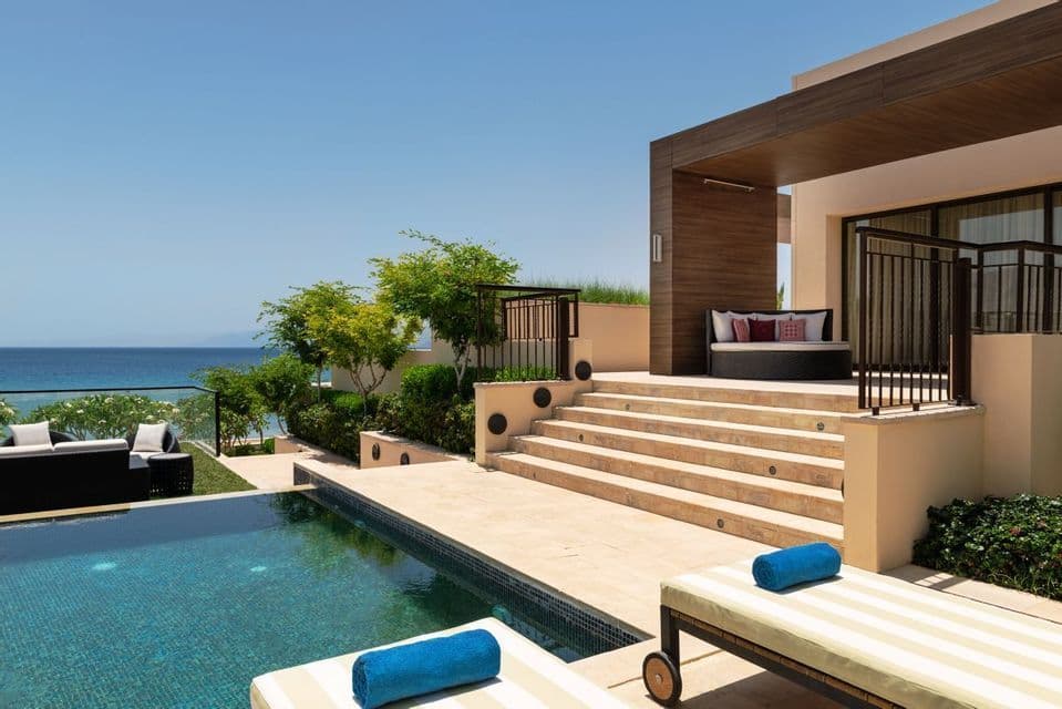 Un moderno patio del resort offre una piscina e lettini con vista sull'oceano.