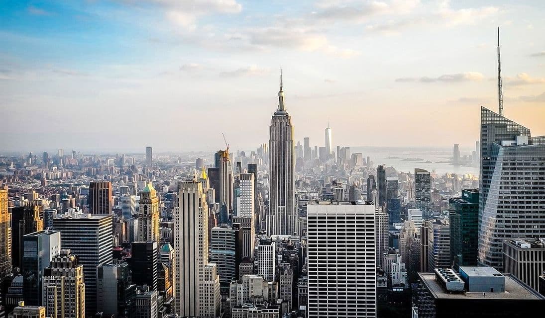 An aerial view of a dense cityscape filled with skyscrapers stretching towards the horizon under a partly cloudy sky.