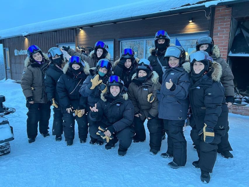 Eine WeRoad-Gruppenreise posiert in Winterjacken und Helmen für ein Gruppenfoto im Schnee.